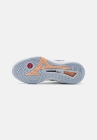 La semelle de la chaussure présente une base blanche avec une semelle extérieure en caoutchouc bleu texturé et un accent orange. Un logo notable en rouge près du talon.