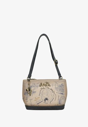 Bolso beis con acentos gris oscuro. Presenta patrones ilustrados y herrajes dorados, incluido un colgante. Cierre de cremallera y correa resistente.