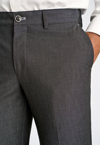 Pantaloni eleganti grigi con texture liscia, caratterizzati da chiusura con bottone, tasche laterali e vestibilità sartoriale per una silhouette moderna.