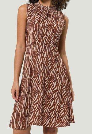 Mouwloze jurk tot de knie met bruin en beige zebra-stripes, geraffineerde halslijn en aansluitende taille op een staand persoon.