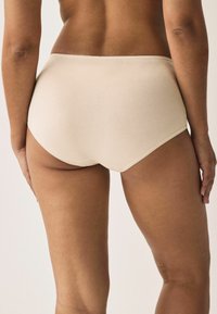Beige high-waisted ondergoed gemaakt van zachte stof. De tailleband heeft een delicate scalloped rand. Glad textuur met minimale naden.