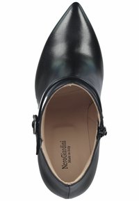Scarpa nera con punta affusolata, esterno in pelle lucida, cinturino alla caviglia e etichetta interna del marchio. Texture liscia con un design strutturato.