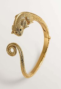 Pulsera de brazalete de metal tono dorado con forma de camaleón, que cuenta con escamas texturizadas y un diseño de cola en espiral para mayor detalle.