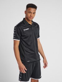 Sort sports polo med korte ærmer og krave. Har hvide accenter og chevronmønstre i grå på skuldrene. Fremstillet af åndbart stof.