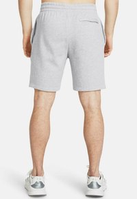Grå bomullsshorts med elastisk midja, två sidofickor, en bakficka och en fållad finish, bärs med vita träningsskor.
