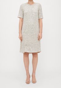 Kortärmad klänning i silverpaljetter, knälång, med rund halsringning och avslappnad passform, som har en slät yta och subtil glans.