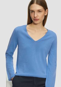 Hellblauer Pullover aus weichem Strickmaterial, mit V-Ausschnitt, langen Ärmeln und lockerer Passform. Minimalistisches Design ohne Muster.