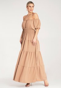 Sukienka maxi w jasnym beżu, bez ramiączek, z bufiastymi rękawami, marszczoną talią i warstwami falban. Gładki, teksturowany materiał.