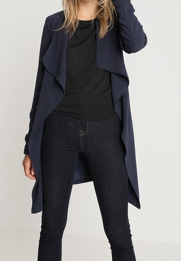 Cardigan léger bleu marine avec un devant drapé, des manches longues et une coupe décontractée, associé à un haut noir et un jean skinny foncé.