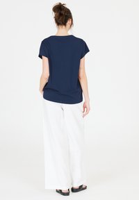Marinblå topp med kort ärm och rund halsringning, i kombination med lösa vita byxor och svarta sandaler. Enkelt designad med en avslappnad passform.