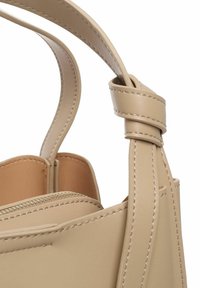 Borsa a mano in pelle beige con un design strutturato, caratterizzata da una tracolla annodata e cuciture in contrasto. Include una tasca con zip e una texture liscia.