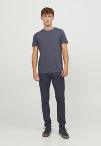 Camiseta a rayas azul marino con escote redondo, combinada con pantalones ajustados azul marino y zapatillas oscuras. Textura suave, diseño casual.