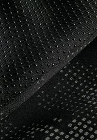 Strukturiert schwarzer Stoff mit zwei Mustern: eines mit erhabenen Punkten und das andere mit kleinen, helleren gedruckten Punkten. Weiches, flexibles Material.