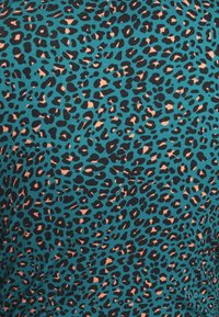 Tissu turquoise avec des taches irrégulières de léopard denses noires et brun clair réparties uniformément sur la surface.