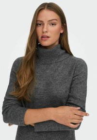 Pull à col roulé gris avec un col côtelé, texture douce et manches longues. Le tissu semble chaud et légèrement moucheté.