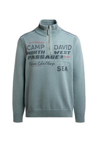 Hellblauer Pullover mit hohem Kragen, Reißverschluss und vorderseitigem grafischen Text in verschiedenen Schriftarten und Farben. Gerippte Bündchen und Saum.