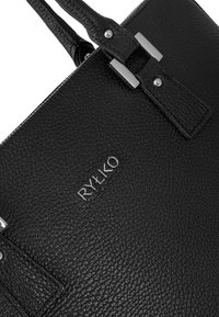 Fekete bőr kézitáska, texturált felülettel, ezüst színű fém elemekkel és a logóval, ami a táska elején van embossed. Kétféle pánttal rendelkezik.