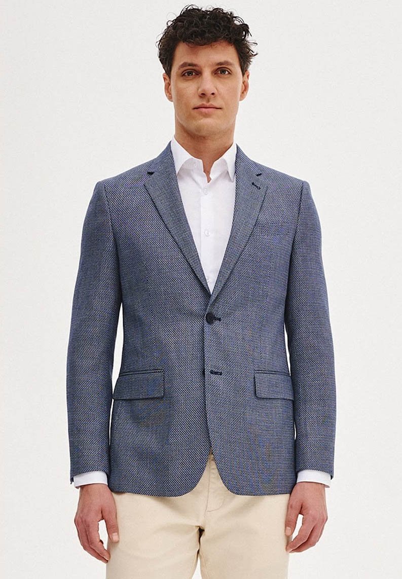 Niebieski teksturowany żakiet o slim fit, z pojedynczym zapięciem na guzik, klapami typu notch oraz dwoma przednimi kieszeniami. Noszony na białej koszuli.