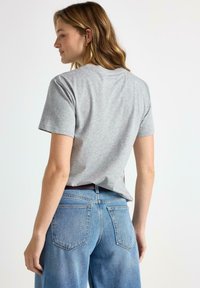 Grå bomulds t-shirt med korte ærmer, rund halsudskæring og en afslappet pasform, parret med højtaljede blå denim jeans med baglommer.