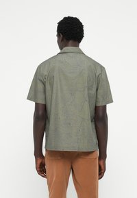 Short-sleeve shirt in olive green with a topographic pattern in dark blue. Features a classic collar and a relaxed fit.