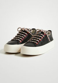Baskets en cuir noir avec une semelle épaisse blanche texturée, ornées de lacets multicolores à motif et de marques en relief sur les côtés.