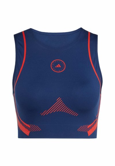 Sportski grudnjak tamnoplave boje s crvenim akcentima. Ima okrugli logotip, glatku teksturu i dijagonalne prugaste uzorke sa strane.