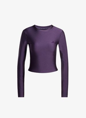 Pitkähihaisiin purple crop topiin, joka on valmistettu sileästä, joustavasta kankaasta. Siinä on pyöreä pääntie ja hienovarainen logo vasemmassa rinnassa.