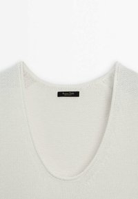 Pull en tricot col en V couleur beige clair; présente une texture respirante et une étiquette avec le nom de la marque 'Massimo Dutti' cousue à l'intérieur de l'encolure.