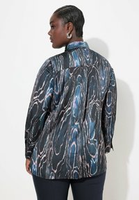 Blusa setosa con sfondo nero e motivo a venature di legno blu e rosa, maniche lunghe e colletto classico.