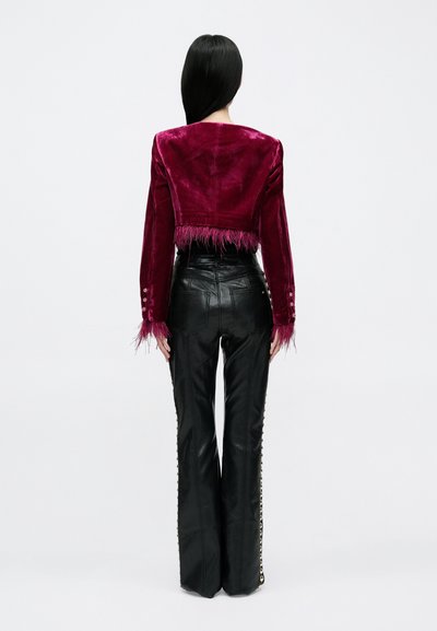 Krótkie bordo aksamitne żakiet z frędzlami na dole i na rękawach, zestawiony z czarnymi wysokim stanem skórzanymi spodniami z bocznymi guzikami.