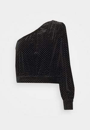 Haut court en velours noir avec une manche longue, présentant des pois argentés et une taille ajustée. Texture lisse et design asymétrique.