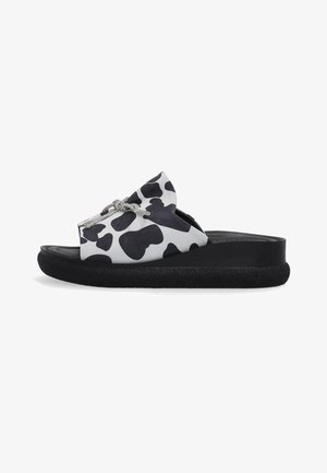 Sort-hvid sandal med køerprint og tyk sort sål samt dekorativt sølvtov over toppen.