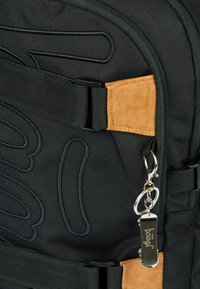 Zaino in tessuto nero con accenti in suede color carta da zucchero, spallacci regolabili e un caratteristico motivo di cucitura decorativa. Rifinito con una zip argentata.