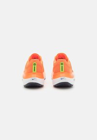 Scarpe da corsa arancione neon con tomaie in rete testurizzata, suole bianche e suola in gomma nera. Presentano accenti verdi e blu.
