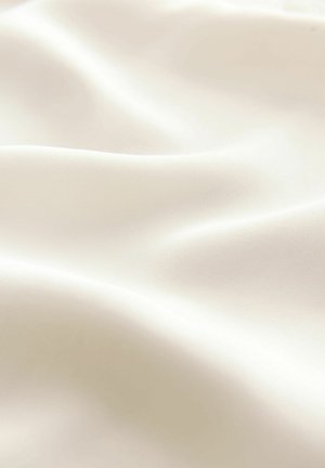 Sileän, valkoinen kangas, jossa on pehmeä textura, jossa on hienovaraisia aaltoja ja taitoksia, heijastaa valoa lempeästi pinnallaan.