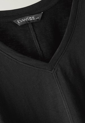 Schwarzes V-Ausschnitt-Oberteil mit sichtbarer Mittelnaht und Etikett, das die Größe UK 18, EUR 46, US 14, Marke Evans zeigt.