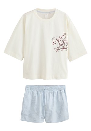 Young woman with medium-length brown hair wearing an oversized white shirt with a black lobster graphic and text on the front.