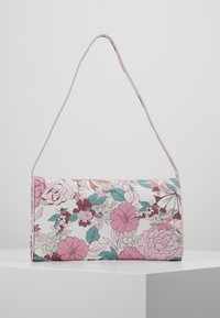 Floral handbag in white faux leather featuring pink, blue, and green flowers. It has a slim, adjustable shoulder strap and a magnetic closure.
