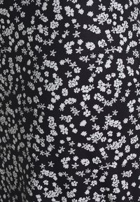 Tela negra con un denso patrón de pequeños racimos de flores blancas y flores en forma de estrella distribuidas uniformemente por toda la superficie.