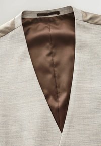 Veste beige clair avec un décolleté en V profond, dotée d'un intérieur en satin marron lisse et d'un tissu texturé subtil à l'extérieur.
