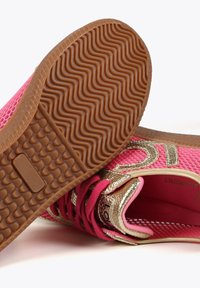 Baskets en mesh rose avec des accents dorés métalliques, semelle en caoutchouc brun texturé et lacets contrastants. Intérieur doublé d'un matériau rose doux.