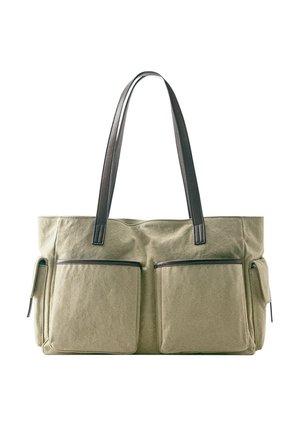 Large olive green canvas tote bag with two front pockets and dark brown leather shoulder straps and trim.