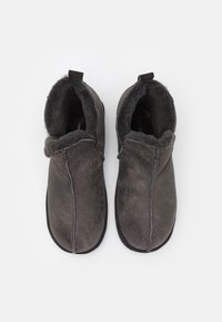 Grijze suède slippers met een zachte, grijze bontvoering, instapontwerp en contrasterende stiksels langs de naden. Platte rubberen zool.