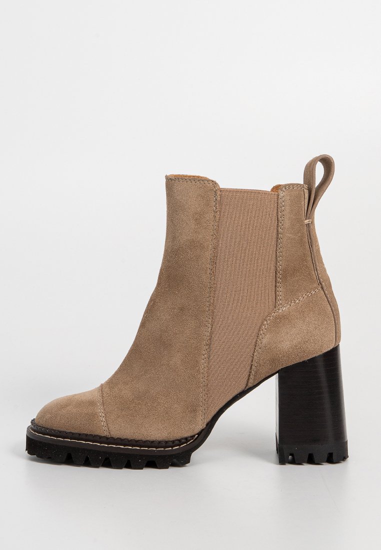 Bottines en suède beige avec des panneaux latéraux élastiques, bout rond et un talon épais noir. Semelle texturée avec une adhérence pour une meilleure traction.