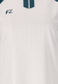 Vit sporttröja med texturmönster, med en turkos design på kragen och sidan samt "FZ"-logotyp i turkos på framsidan.