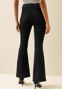 Zwarte flared jeans van denim, met een hoge taille, vijf zakken en een gladde textuur. Draag ze met zwarte hoge hakken.