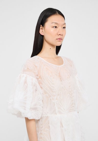 Robe blanche transparente avec des volants texturés, des manches bouffantes et un col arrondi. Tissu léger avec un design délicat et aérien.