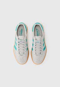 Grå ruskind sneakers med turkise striber, der har snørebånd, polstret krave og en gummi sål.