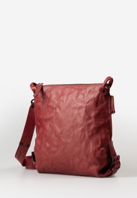 Rote Leder-Umhängetasche mit strukturiertem Finish, Oberreissverschluss und verstellbarem Tragegurt. Mit abgerundeten Ecken und seitlichen Akzenten.