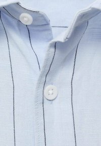 Lichtblauwe button-up shirt met een zachte textuur, smalle zwarte verticale strepen en witte knopen bij de kraag.